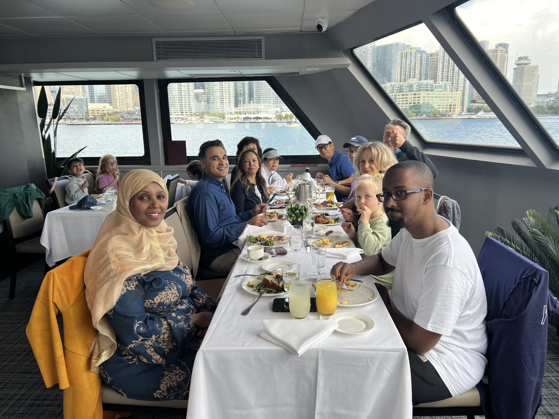 a group of people sitting at a table with food on a boat